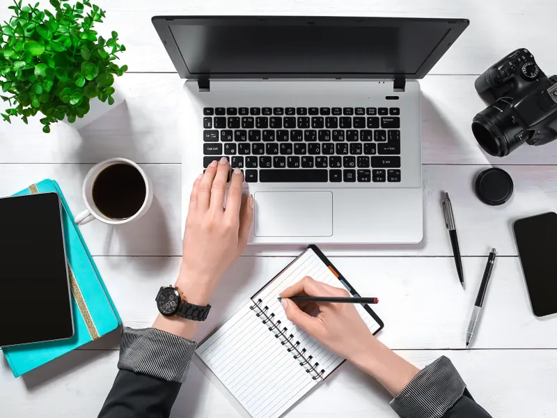 Marketing planning at a desk with laptop, notebook and camera